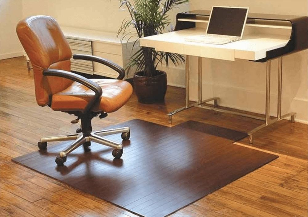 An image of a computer chair on top of a floor mat.