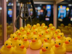 Brightly colored duck-themed claw machine filled with yellow duck plush toys and prizes