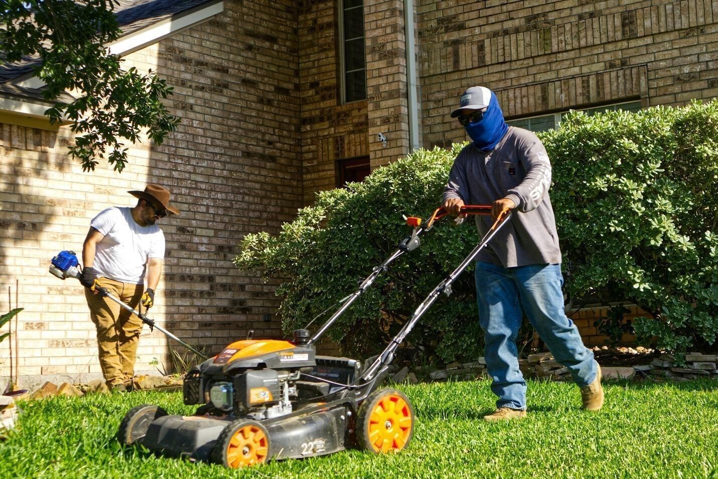 Two men mowing and trimming a residential lawn Two men mowing and trimming a residential lawn